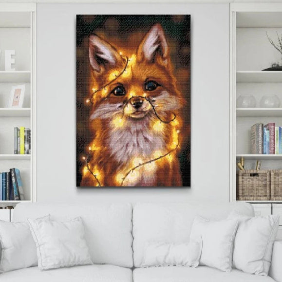 Diamanttavla av en söt räv med stora ögon, insvept i varma ljusslingor mot mörk bakgrund.