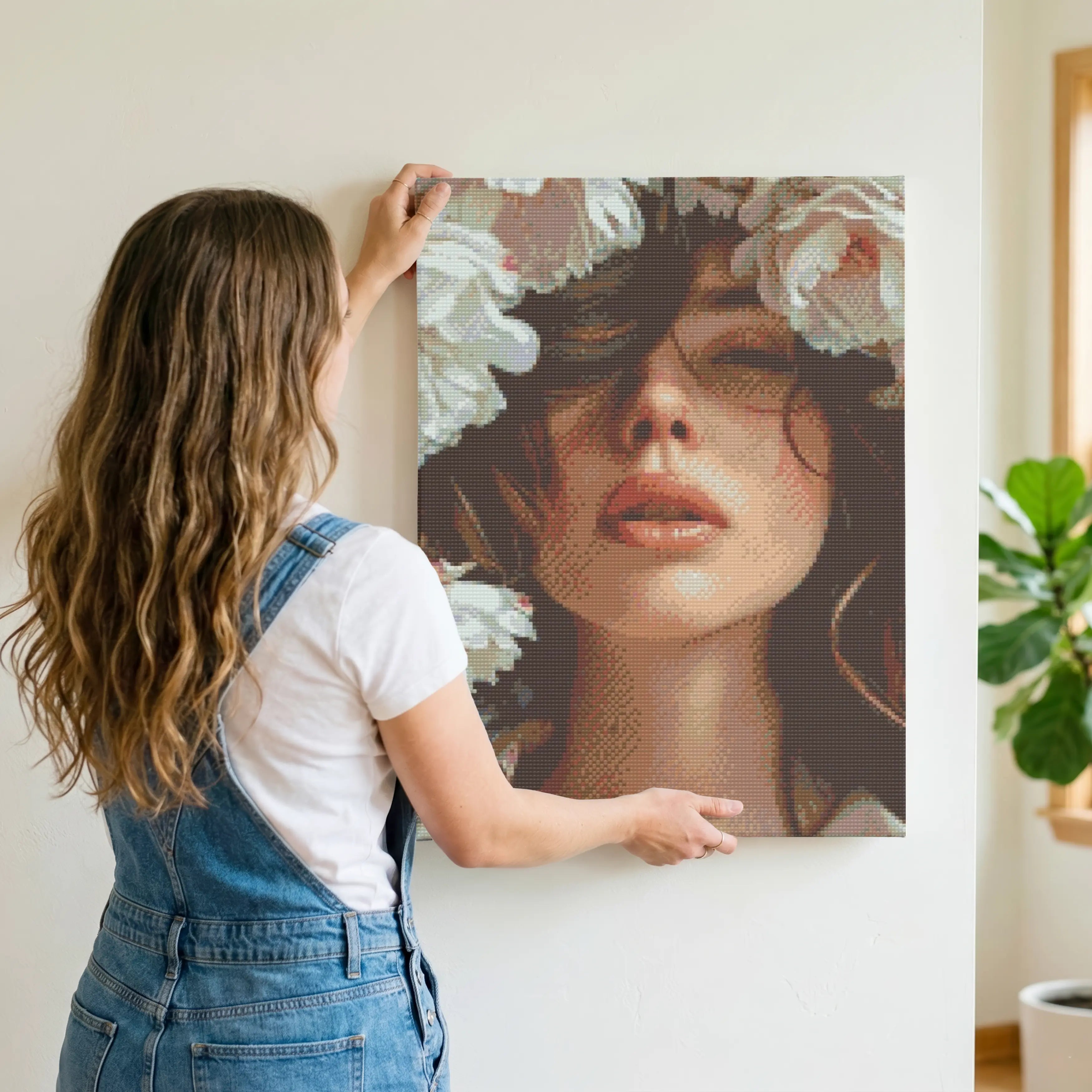 Woman hanging a portrait of a woman with flowers on a wall Flora Veil | Diamond Painting Kit